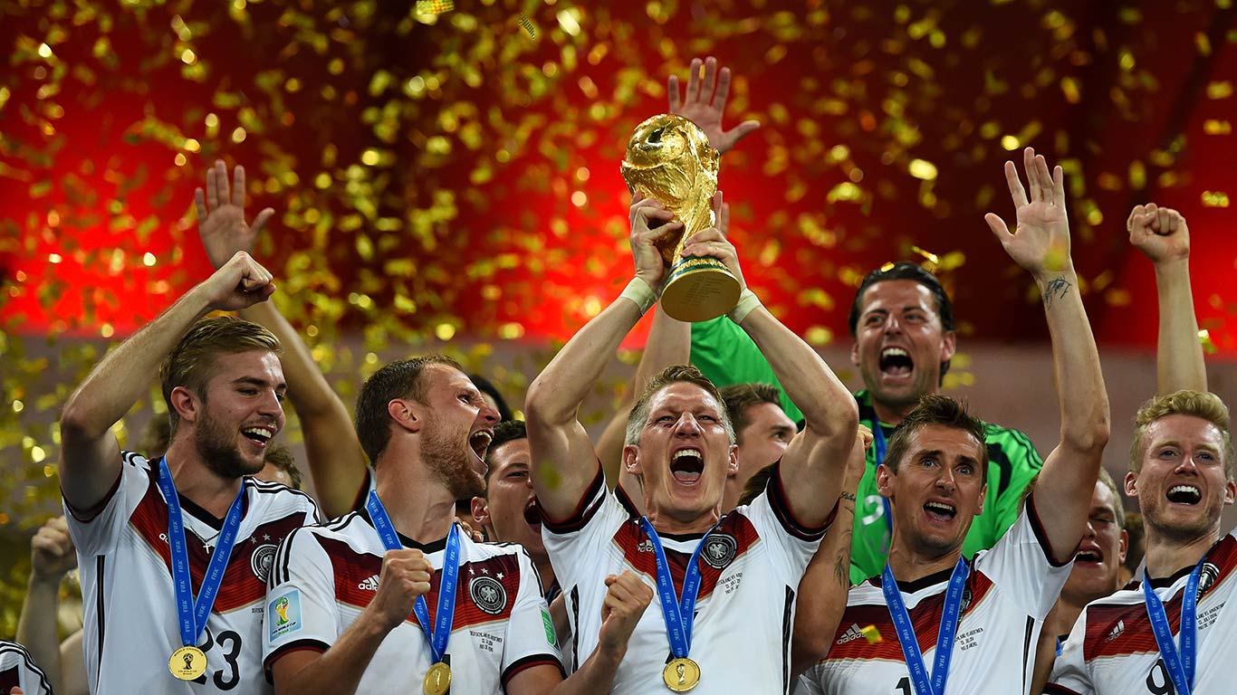 Bastian Schweinsteiger stemmt den WM-Pokal in die Höhe und feiert mit seinen Nationalmannschaftskameraden den Sieg im Finale der FIFA-Fußball-Weltmeisterschaft 2014 gegen Argentinien im Maracana-Stadion in Rio de Janeiro, Brasilien, am 13.7.2014 (© Shaun 