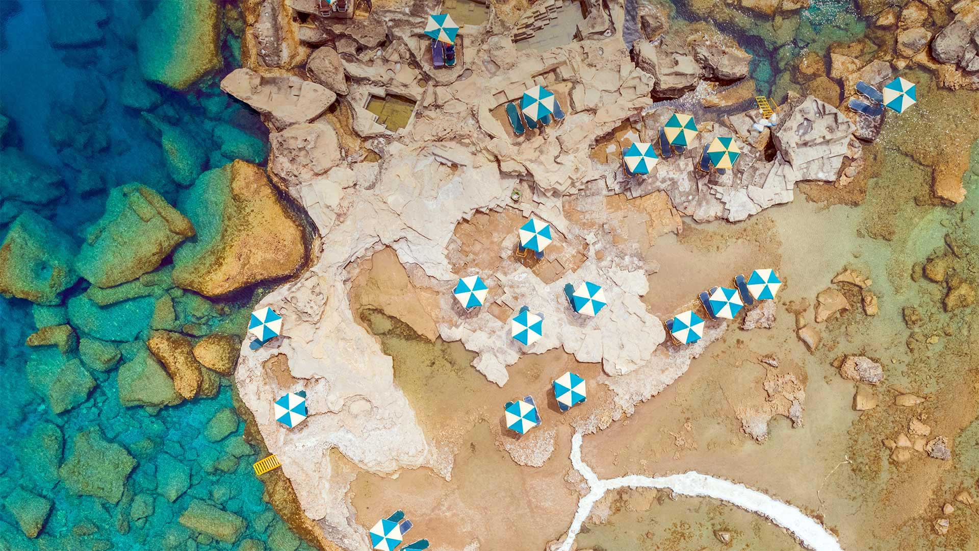 鸟瞰希腊罗德岛岩石海岸上蓝白相间的遮阳伞 (© Amazing Aerial Agency/Offset by Shutterstock)(Bing China)