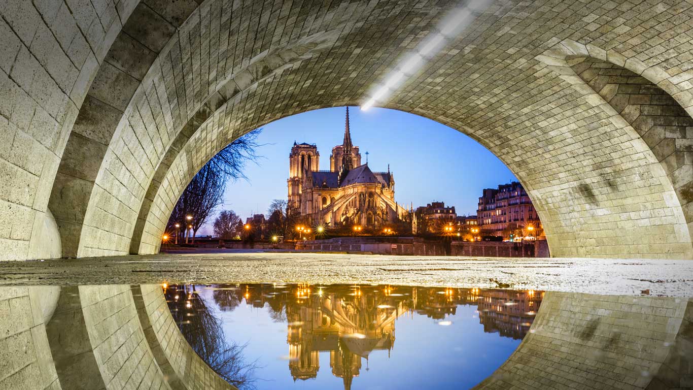 Notre-Dame de Paris se reflétant dans l’eau sous le pont de la Tournelle la nuit, Paris, Île de France (© Loic Lagarde/Getty Images)(Bing France)