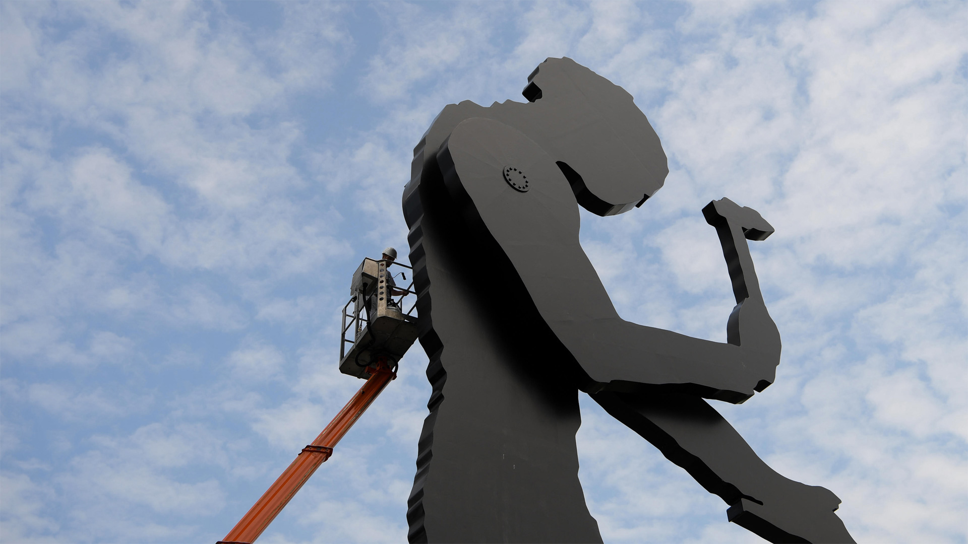 A worker painting the Hammering Man, a sculpture by Jonathan Borofsky, in Frankfurt, Germany (© Arne Dedert/Alamy)(Bing Canada)