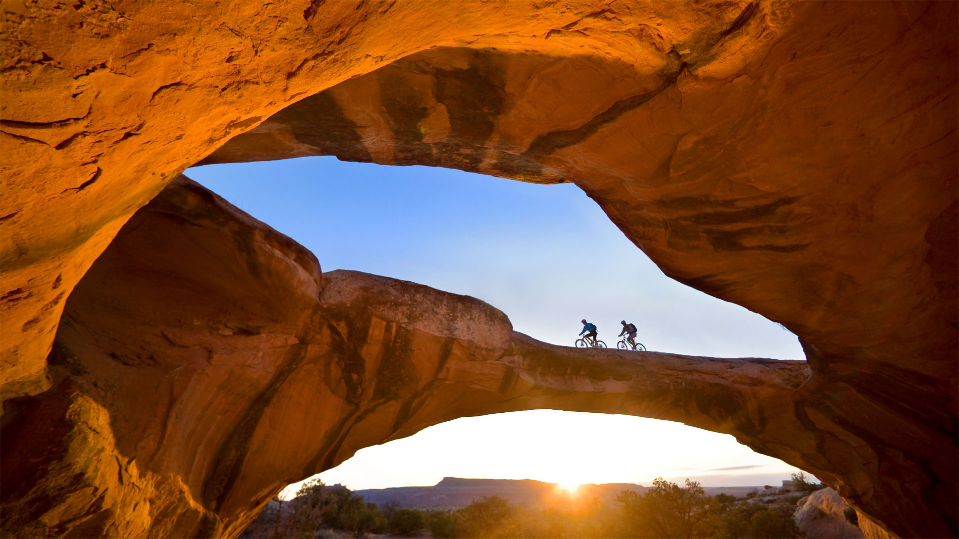 Cycling across a natural rock arch in the desert near Moab, Utah (© Whit Richardson/Cavan)(Bing Canada)