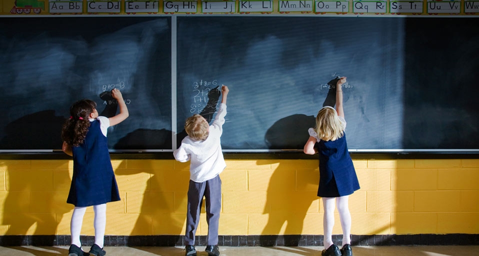 Three students writing on blackboard in classroom -- Ron Levine/Photodisc/Getty Images &copy; (Bing Australia)